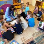 Dzieci z grupy przedszkolnej słuchają bajek czytanych przez bibliotekarza.