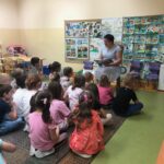 Przedszkolaki słuchają bajek czytanych przez bibliotekarza