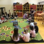 Przedszkolaki słuchają bajek czytanych przez bibliotekarza